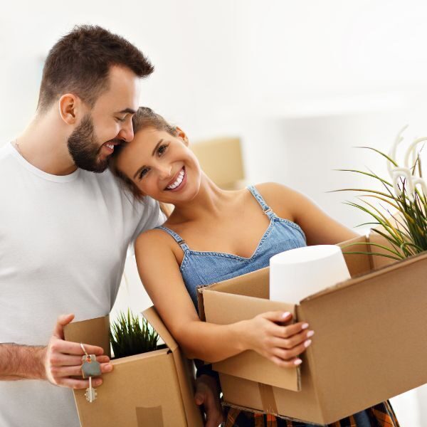 Couple holding moving boxes in a new home before a move-in cleaning